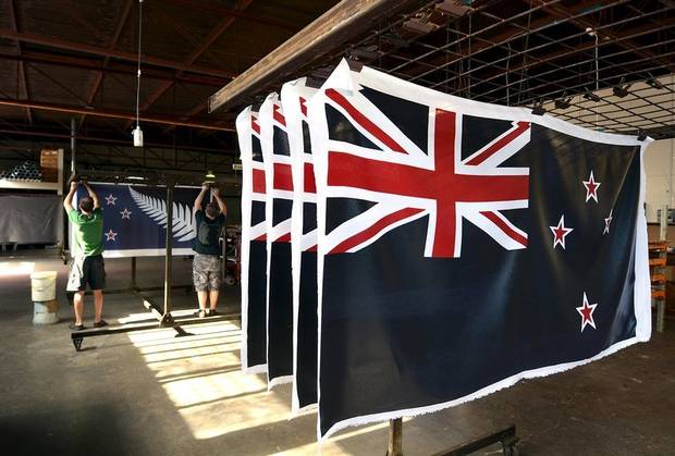 Factory workers Garth Price and Andrew Smith hang old and new designs of the national flag of New Zealand at a factory in Auckland on Nov. 24, 2015.