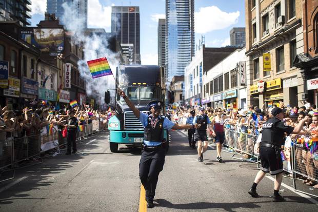 A Toronto Police Service parking enforcement officer waves a Pride flag as they march along the parade route during the Pride Parade in Toronto, Sunday, July 3, 2016.
