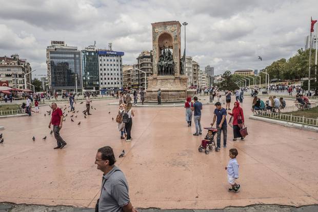 Pedestrians walk past the monument of the Republic on Taksim Square in Istanbul.