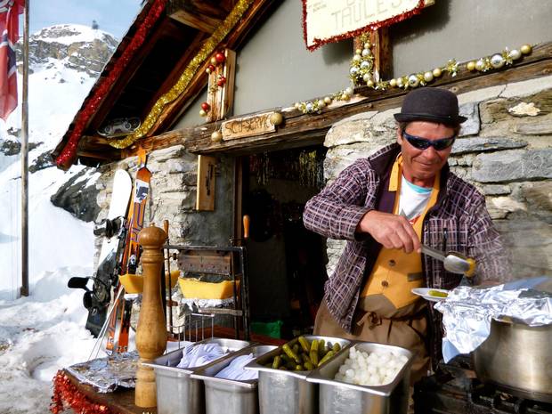Thomas, manager of Cabane des Taules, prepares raclette outside a bare-bones shed; it’s a popular location even without a formal patio.