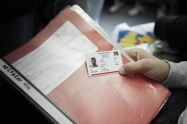 Basel Omran holds his paperwork and an ID card issued by the security service at his German refugee camp.