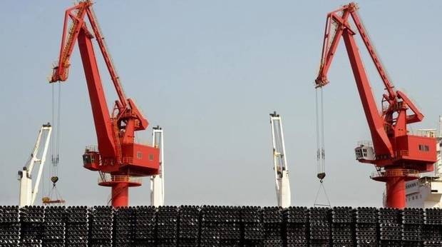 Piles of steel pipes to be exported are seen in front of cranes at a port in Lianyungang, Jiangsu province March 7, 2015.