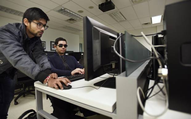 Assistant Jimil Desai, left, helps Zeeshan connect cables and hard drives for his computer lab classes.