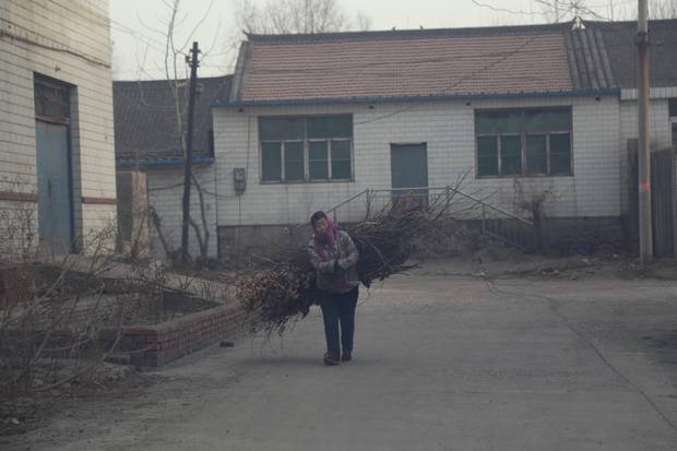A villager hauls wood through smog-filled air to burn for cooking in Songting village.