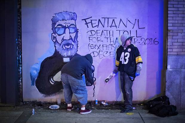 Artist Smokey D, left, paints an anti-fentanyl art piece while his friend, Danny, keeps watch for police in Vancouver’s Downtown Eastside on Dec. 22, 2016.