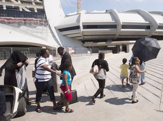 A group of asylum seekers leave Olympic Stadium, which has been set up as a temporary shelter.