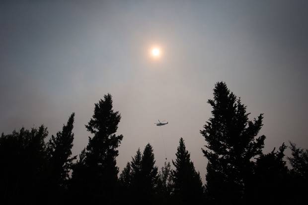 July 8, 2017: Smoke obscures the sun as a helicopter carrying a bucket battles the Gustafsen wildfire near 100 Mile House, B.C.