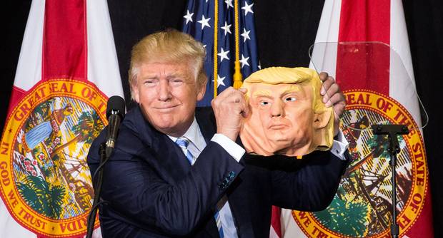 Donald Trump holds up a mask of himself at the Sarasota Fairgrounds in Sarasota, Fla., on Nov. 7, 2016.
