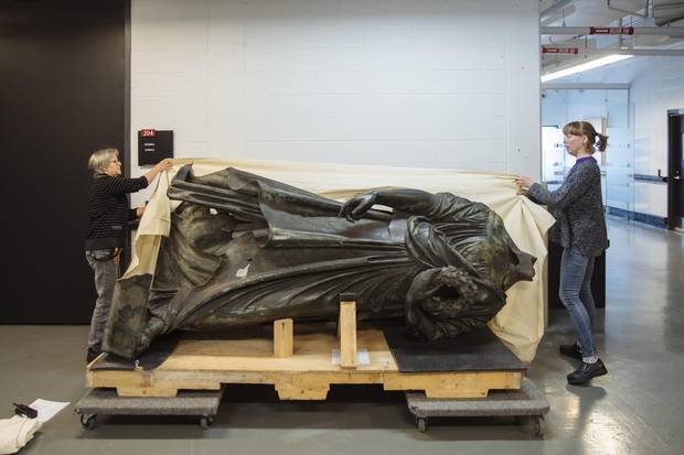 Museum technicians Helene Giguere, left, and Roxanne Bellemare, right, remove a protective tarp from the body of the Queen Victoria statue at the Musee de la Civilization archives in Quebec City on Monday, May 15, 2017. 