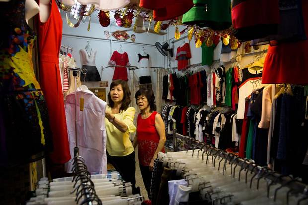A vendor looks at clothing in a store at the Teck Ghee Court Market & Food Centre in the Ang Mo Kio area of Singapore, on Saturday, Feb. 20, 2016.