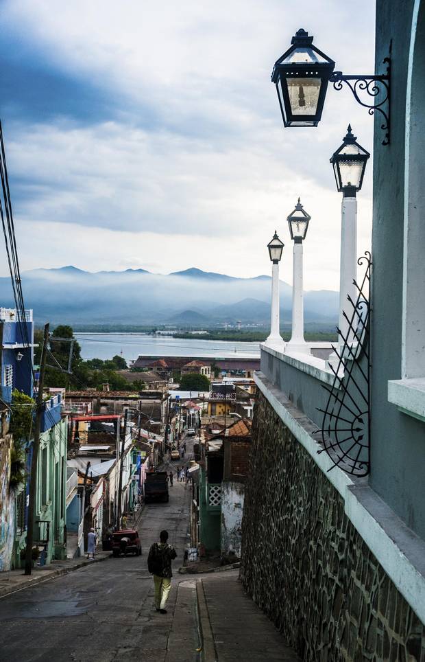 The majestic Sierra Maestra mountains rise in contrast against the humble streets of Santiago de Cuba.