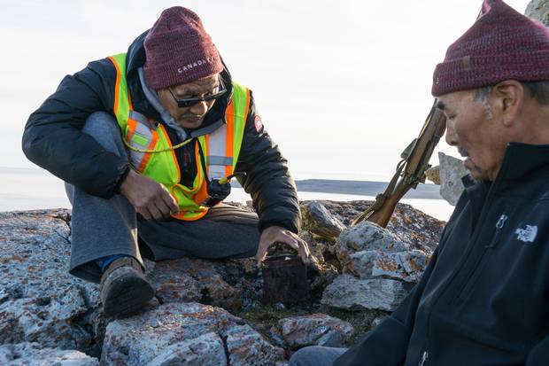 Roger Hitkolok, right, and Jimmy Evalik inspect a tin can at a cairn on Sutton Island, Nunavut. The can contained a note from a captain who had moored at the island to weather a storm.