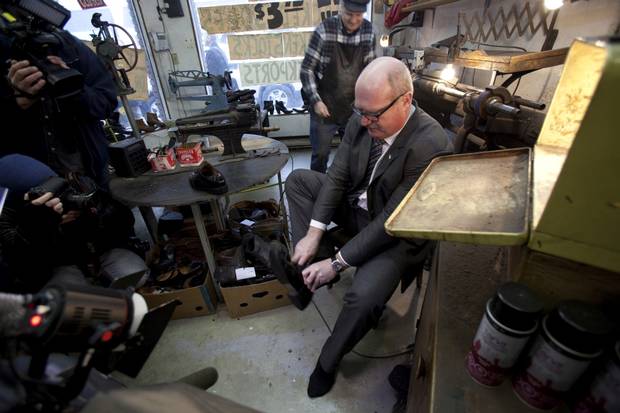 Finance Minister Michael de Jong tries on his newly-soled shoes at Olde Towne Shoe Repair in Victoria as owner Mike Waterman looks on. The photo-op has become a yearly ritual ahead of the provincial budget.