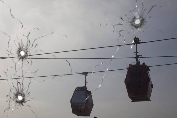 Cable cars move along, seen through a window pierced by bullet holes, on July 24, 2012, at a police station used by the UPP in Rio’s Complexo do Alemao slum.
