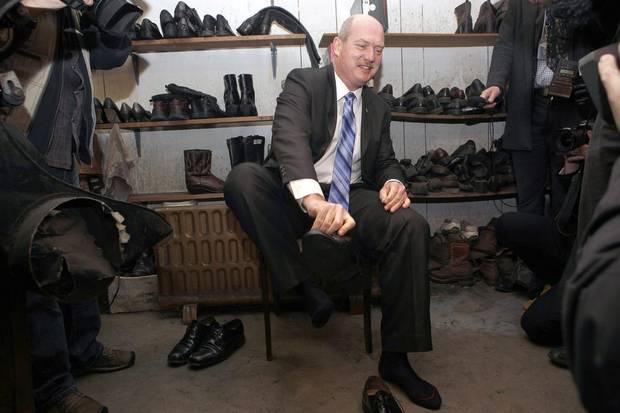 B.C. Finance Minister Mike de Jong tries on his 2015 budget shoes – resoled older shoes – at Olde Town Shoe Repair in Victoria on Feb. 16, 2015.