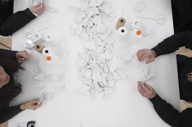 Visitors to Yoko Ono's Mend Piece exhibit at the Rennie Museum in Vancouver on Feb. 28 attempt to reassemble shards of ceramic tea cups and saucers using the provided twine and glue.