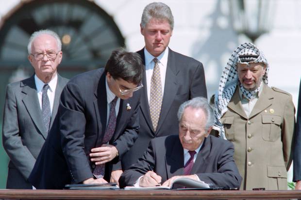 Mr. Peres, middle, the historic Oslo agreement at the White House on Sept. 13, 1993. Behind him are Israeli prime minister Yitzhak Rabin, an unidentified aide, U.S. president Bill Clinton and PLO chairman Yasser Arafat.