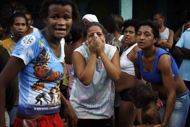 Residents react during a shootout involving police and suspected drug traffickers at the Complexo de Alemao slum in Rio de Janeiro on June 27, 2007. Police killed at least 18 suspected drug traffickers in the massive operation.