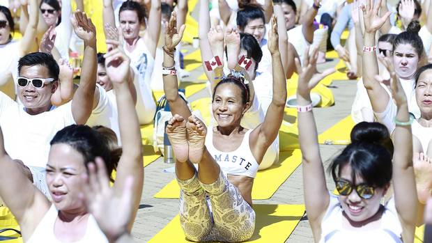 Carol Ip sports Canadian flags on her head as she joins hundreds of other people as they they participate in a group yoga session celebrating Canada's 150th birthday as a community at the McArthurGlen Designer Outlet on July 1, 2017 in Richmond, Canada. (Photo by Jeff Vinnick/Getty Images)