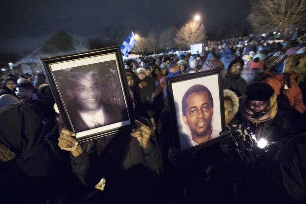 Rosa Pola, left, holds up a photo of Mamadou Tanou Barry and Aissatou Cisse holds up photo of Ibrahim Barry (no relation to Tanou) during a vigil in Quebec City on Jan. 30, 2017.