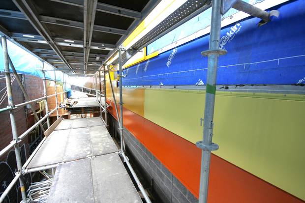 Behind the tarpaulin and the scaffolding, the colours take shape on the east wall of the Kensington Market Lofts.