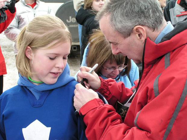 Ron MacLean of CBC's Hockey Night in Canada signs a young fans jersey in Shaunavon Saskatchewan as they get ready for CBC's Hockey Day in Canada broadcast.