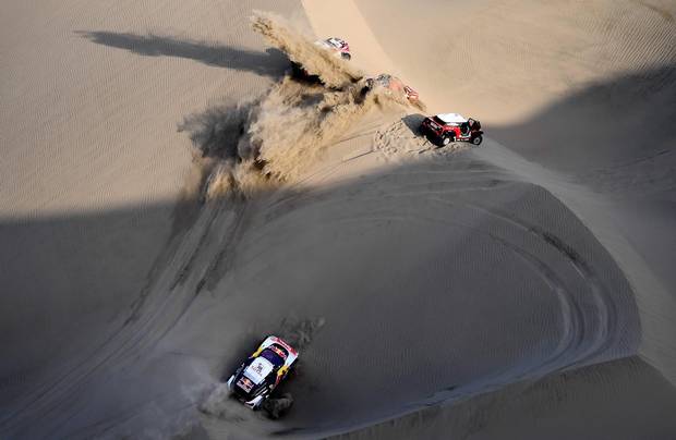 TOPSHOT - Peugeot's French driver Sebastien Loeb and co-driver Daniel Elena from Monaco (bottom) get stuck in the sand and other competitors pass by during the 2018 Dakar Rally Stage 5 between San Juan De Marcona and Arequipa in Peru, on January 10, 2018. Sebastien Loeb was forced to pull out of the Dakar Rally after a back injury suffered by his co-driver in a disastrous fifth stage won by defending champion Stephane Peterhansel.