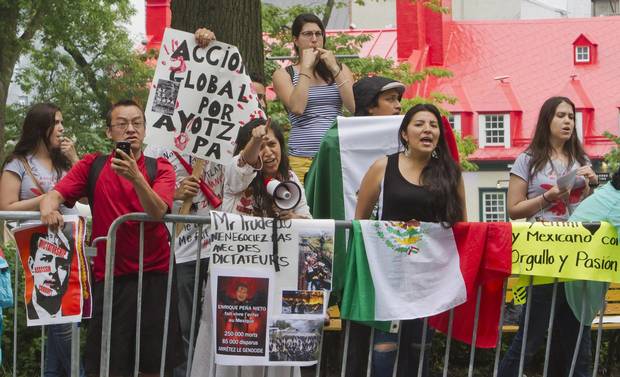 People protest against a visit by Mexico President Enrique Pena Nieto in Quebec City, Monday, June 27, 2016.