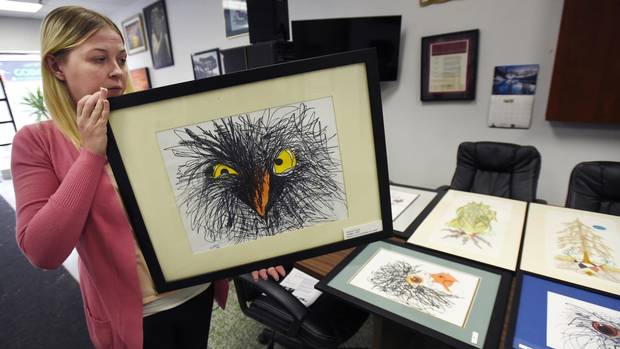Natasha Smith, employment co-ordinator for The Bridge, holds Angry Birds, a work by Wayne Forest, at show of prisoner art in Brampton, Ont.