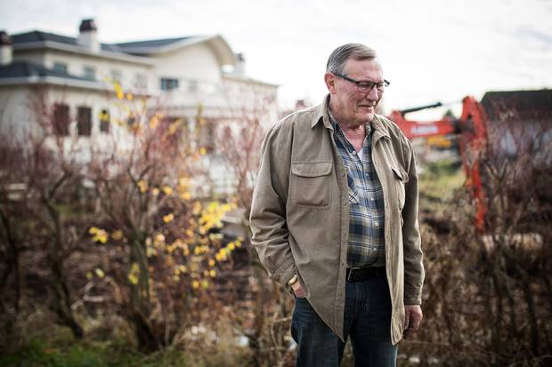 The mansion next door looms behind beekeeper Bob Fisher on his property in Richmond, B.C.