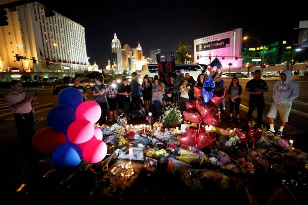 People gather at a makeshift memorial in the middle of Las Vegas Boulevard.