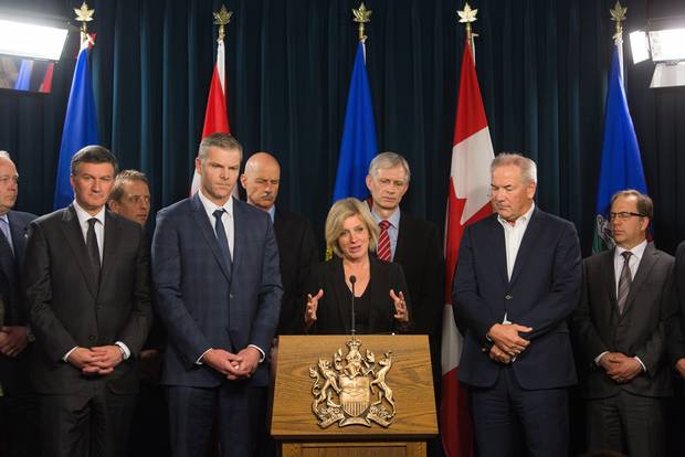Premier Rachel Notley speaks to the media along with Suncor President and CEO Steve Williams, right, and President and CEO Canadian Association of Petroleum Producers Tim McMillan, left, at the Alberta Legislature in Edmonton, Alberta, on Tuesday, May 10, 2016. They met to discuss recovery strategies, including prioritizing restarting industrial activities, moving forward in Fort McMurray after the devastating wildfires.