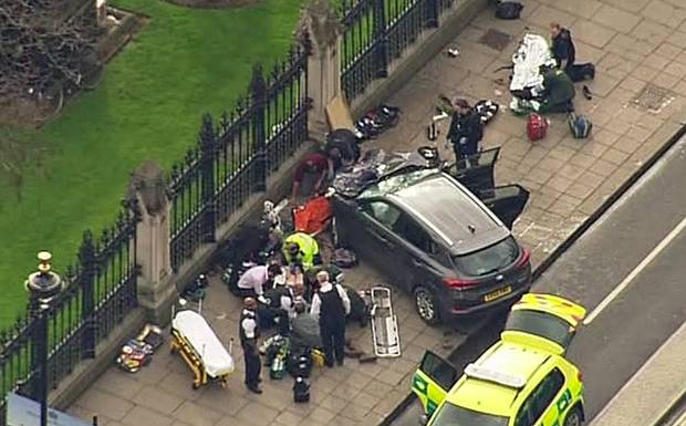 In this image taken from video police officers gather around a car adjacent to Houses of Parliament in London after the House of Commons sitting was suspended as witnesses reported sounds like gunfire outside.