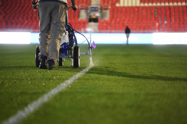 The ground crew works late into the night measuring and painting lines on the field.