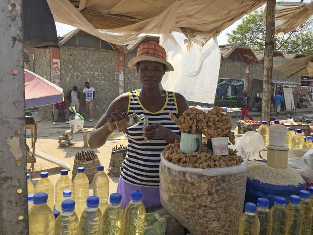 Anna Magaya measures cooking oil into perfume bottles in an outdoor market in the town of Chitungwiza, near Harare.