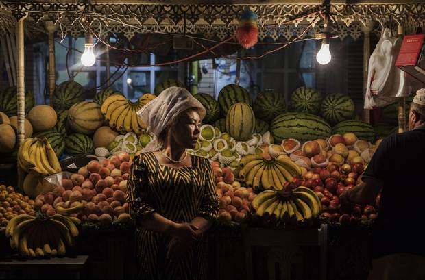 An ethnic Uyghur woman waits for customers at her fruit stand on June 27, 2017 in the old town of Kashgar, in the far western Xinjiang province, China. 