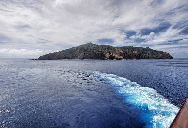 A ship turns as it passes a Pacific island.
