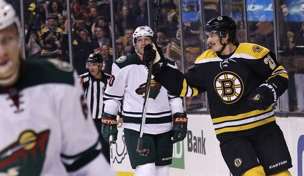 Boston Bruins left wing Loui Eriksson, right, skates past Minnesota Wild defenseman Ryan Suter, center, after scoring his first goal of the game during the second period of an NHL hockey game in Boston Thursday, Nov. 19, 2015. Eriksson had a hat trick in the game. (AP Photo/Charles Krupa)