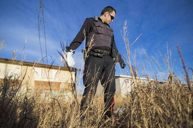 Constable Rayan Najjar with the Blood Tribe Police Service looks for used needles near an abandoned house.
