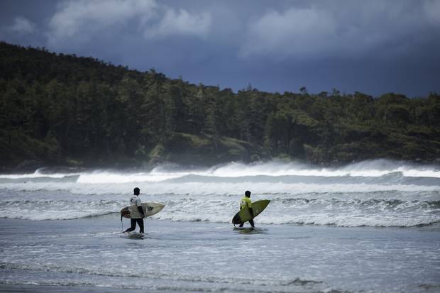 Surfers stride through the waves to begin as competition begins at the Rip Curl Pro Tofino Canadian Surfing Championships on Cox Bay Beach