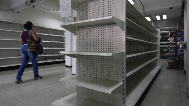 A woman walks past empty shelves at a drugstore in Caracas, February 23, 2016.
