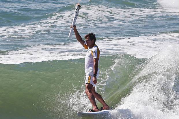 Brazilian surfer Carlos Burle holding the Olympic torch as it visits Porto de Galinhas, Ipojuca, in the Brazilian norteastern state of Pernambuco.