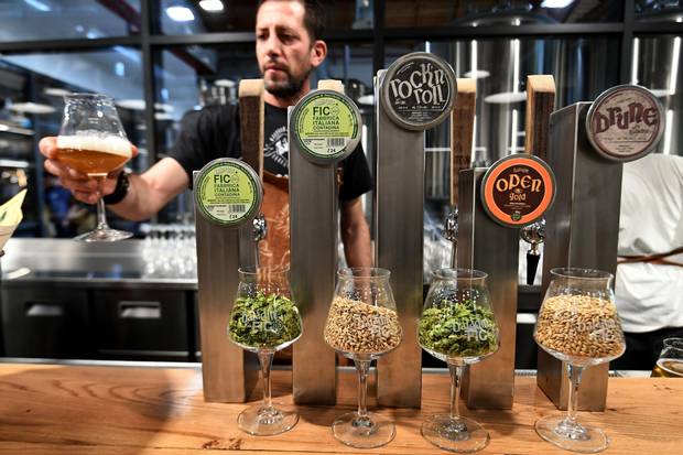A man offers a glass of artisanal beer at a stand during a press tour at FICO Eataly World agri-food park in Bologna on November 9, 2017. FICO Eataly World, said to be the world's biggest agri-food park, will open to the public on November 15, 2017.