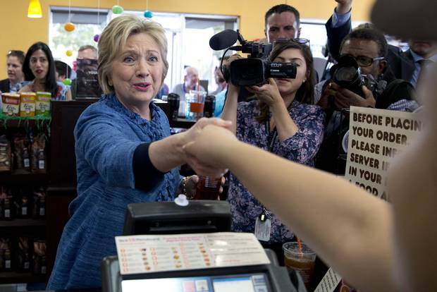 Democratic presidential candidate Hillary Clinton reaches to shake hands with an employee behind the counter during a visit to Dunkin' Donuts in West Palm Beach, Florida ahead of the state primary.