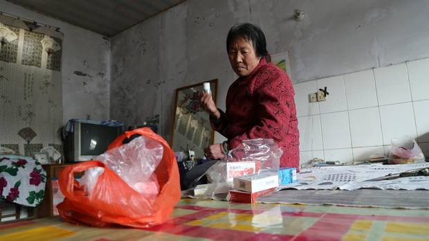 Pi Fengqin, a resident of Songting, sorts through some of the medication she takes for heart and brain ailments she says have grown worse in the smog.