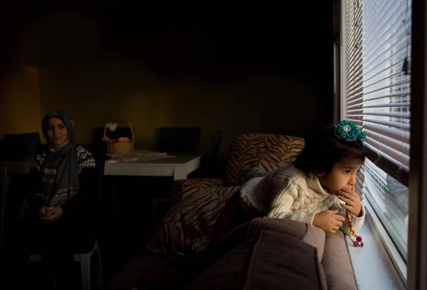 Karim Dalaa, 3, looks out the window at home as her mom Zamzam Dalaa looks on in Edmonton, Alberta in December 2015. The newly arrived refugees were sponsored by a local community group.