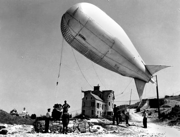A tethered barrage balloon is deployed to ward German planes away from Allied ships unloading troops and supplies in Normandy.