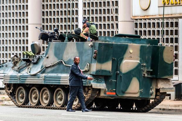 Nov. 16: A man walks past a military tank parked on the side of a Harare street.