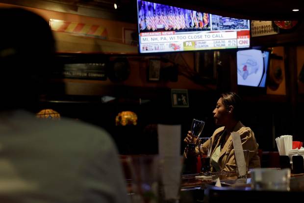 A woman looks on as a screen displays election results at a bar in Tijuana on Nov. 8, 2016.