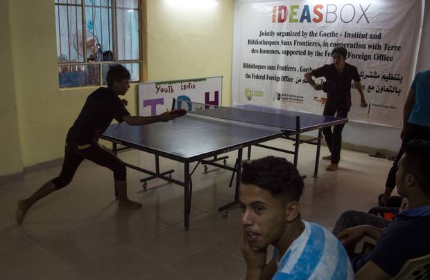 Iraqi youth, who were separated from their families during the fighting, play ping pong at the headquarters of the Terres des Hommes Italia, July 16, 2017, southeast of Mosul.